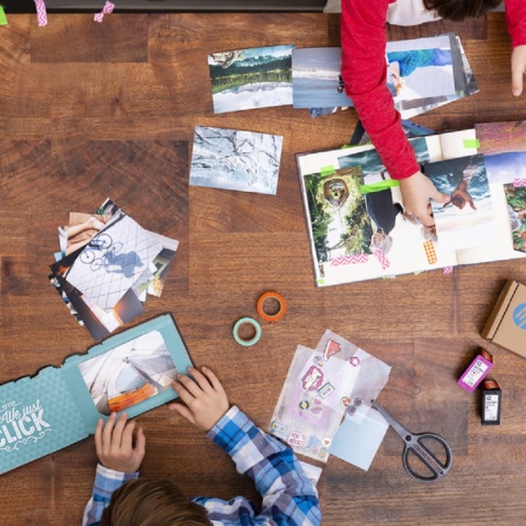 Ξύλινο τραπέζι με τυπωμένες φωτογραφίες και ανθρώπους που πιάνουν πράγματα