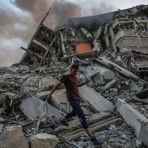 Παλαιστίνιος περπατά πάνω στα ερείπια κτιρίου που κατέρρευσε στη Λωρίδα της Γάζας μετά από αεροπορικό βομβαρδισμό του Ισραήλ