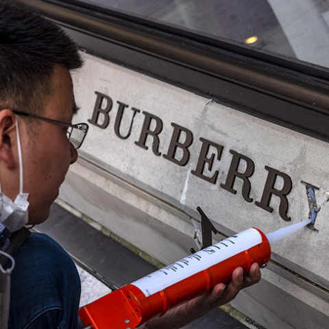 Ένας άντρας επισκευάζει κατεστραμμένο λογότυπο μπροστά από το κατάστημα Burberry στη Σαγκάη της Κίνας, στις 26 Μαρτίου 2021.