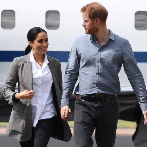 Η Μέγκαν Μαρκλ και ο πρίγκιπας Χάρι περπατούν με φόντο ένα αεροπλάνο