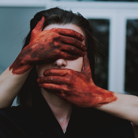 Χέρια με αίματα καλύπτουν πρόσωπο γυναίκας