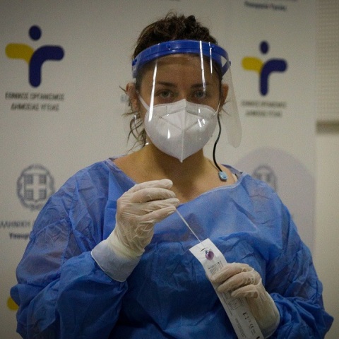 Γυναίκα διενεργεί rapid test φορώντας μάσκα και γάντια