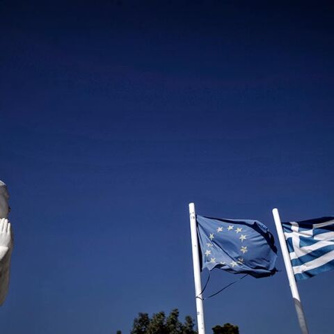 Οι σημαίες της Ελλάδας και της Ευρωπαϊκής Ένωσης κυματίζουν πίσω από το άγαλμα στο Μνημείο Πεσόντων στην Μηλίνα Πηλίου.