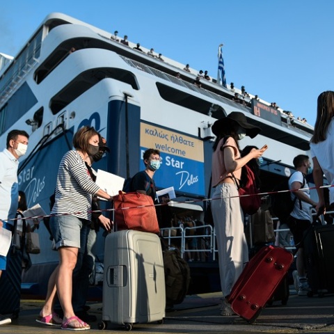 Ταξιδιώτες αναμένουν την επιβίβασή τους σε πλοίο κρατώντας στα χέρια κινητό ή έγγραφα που χρειάζονται