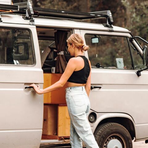 Κοπέλα με τζιν και μαύρη μπλούζα μπροστά από βανάκι στη φύση