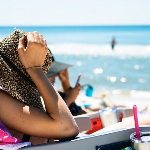 Μια κοπέλα απολαμβάνει τον ήλιο στην παραλία.