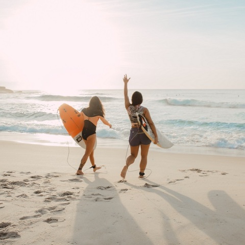 Κορίτσια ετοιμάζονται να βουτήξουν με τη σανίδα του surf στην παραλία.