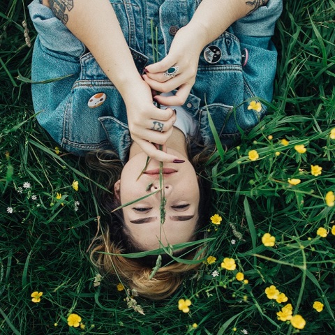 Μια γυναίκα ποζάρει ανάμεσα στα λουλούδια.