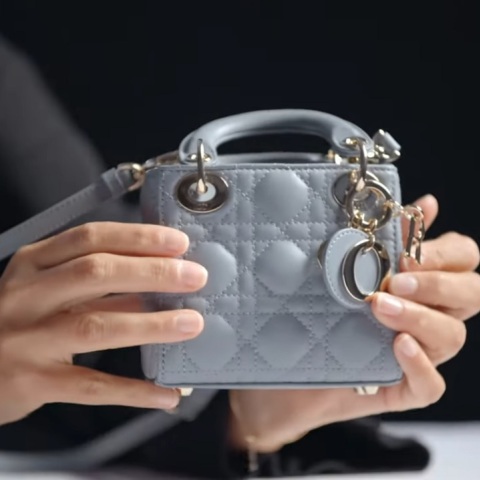 Γυναίκα κρατάει μινιατούρα τσάντα Dior