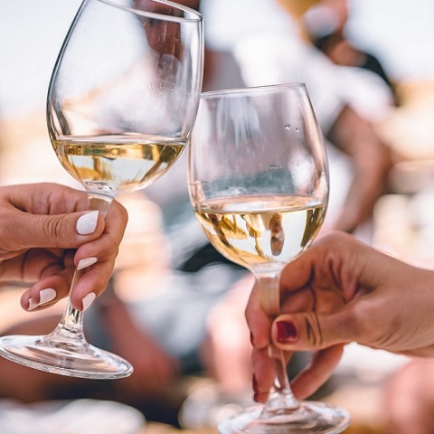 Δυο κορίτσια κρατούν ποτήρια με λευκό κρασί.