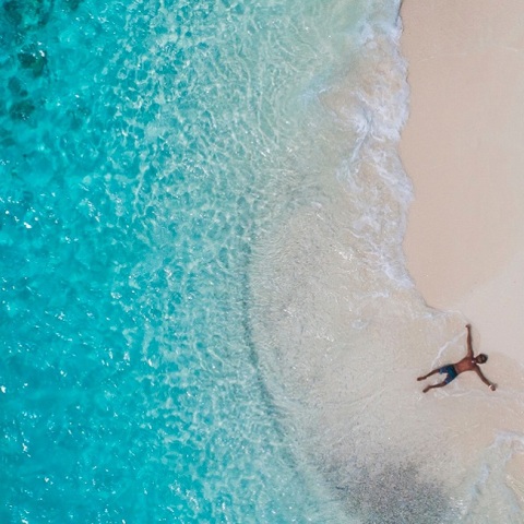 Ένας ανδρας ξαπλώνει στην παραλία και απολαμβάνει τη θάλασσα.