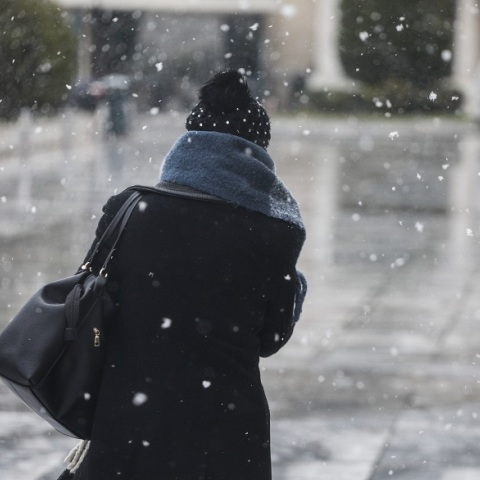 Γυναίκα περπατά στο δρόμο υπό χαμηλές θερμοκρασίες και χιονόπτωση