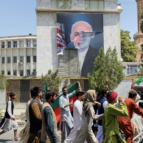 Αφγανοί προσπερνούν την αφίσα του Αφγανού προέδρου Ασράφ Γκανί που εγκατέλειψε τη χώρα μετά την ανάληψη των Ταλιμπάν © EPA / STRINGER