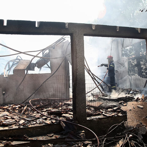 Καμένο κτίριο στα Βίλια, με πυροσβέστη να ρίχνει νερό - Σαρωτικό το πέρασμα της νέας φωτιάς