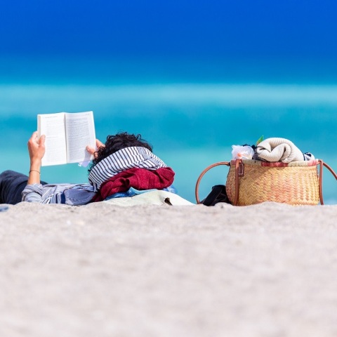 Ένας άνδρας διαβάζει ένα βιβλίο στην παραλία.