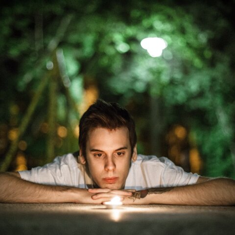 Άνδρας που είναι ξαπλωμένος και κοιτά αναμμένο κερί