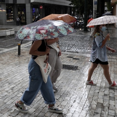 Γυναίκες προστατεύονται από την καταιγίδα κρατώντας ομπρέλα