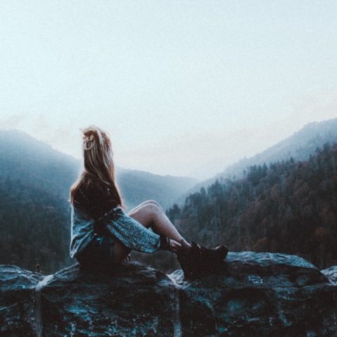 Μια κοπέλα κάθεται σε ένα βράχο 