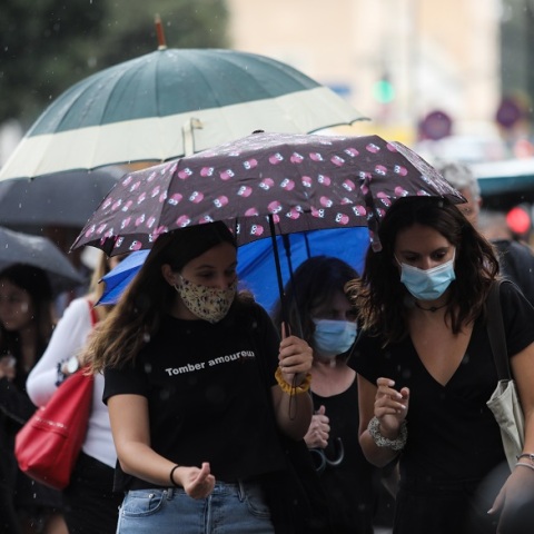 Πολίτες κρατούν ομπρέλα για να προστατευτούν από τον βροχερό καιρό