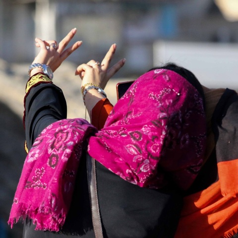 Γυναίκα με μαντήλα βγάζει σέλφι φωτογραφία σχηματίζοντας το σήμα της νίκης