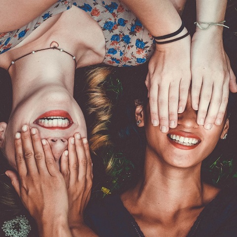 Δύο γυναίκες χαμογελάνε ενώ κλείνουν τα μάτια η μια στην άλλη 