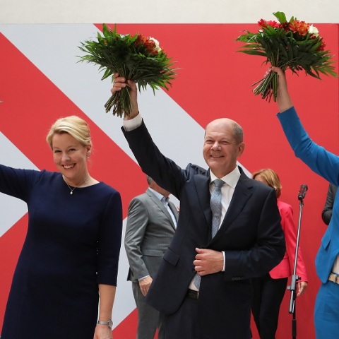 Ο Όλαφ Σολτς και το επιτελείο του υψώνουν το χέρι τους κρατώντας ανθοδέσμες