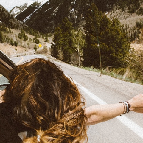 Μια κοπέλα βγάζει το χέρι από το παράθυρο κατά τη διάρκεια ενός roadtrip. 