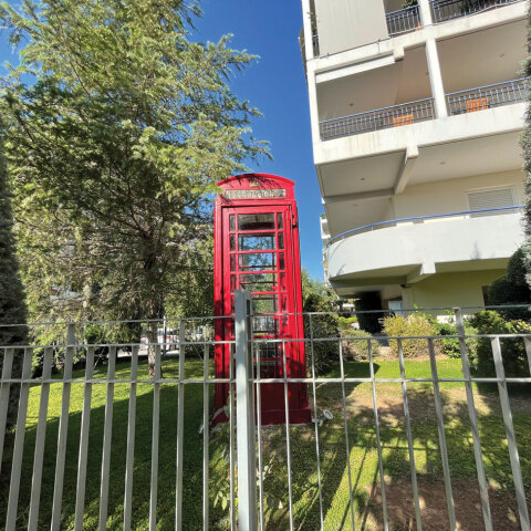 Κόκκινος τηλεφωνικός θάλαμος σε αυλή πολυκατοικίας στις Τζιτζιφιές