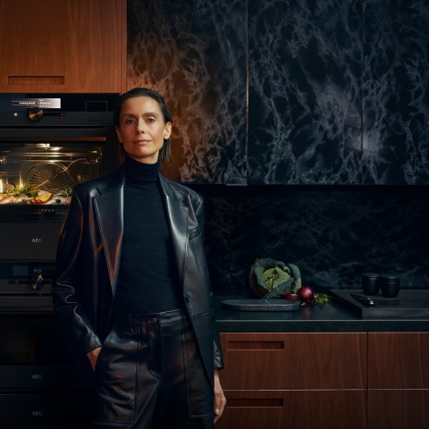 Γυναίκα με μαύρα ρούχα στέκεται μπροστά από φούρνο AEG που λειτουργεί