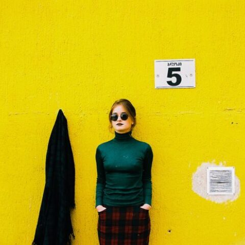 Γυναίκα που φορά γυαλιά ηλίου με φόντο κίτρινο τοίχο