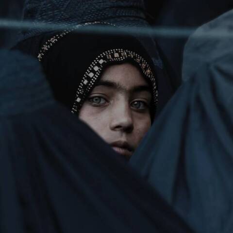 Ένα κορίτσι κοιτάζει ανάμεσα από άλλες Αφγανές γυναίκες 