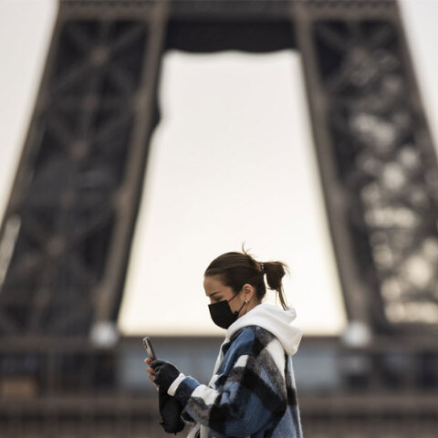 Κοπέλα με μάσκα για τον κορωνοϊό περνά μπροστά από τον Πύργο του Άιφελ στο Παρίσι
