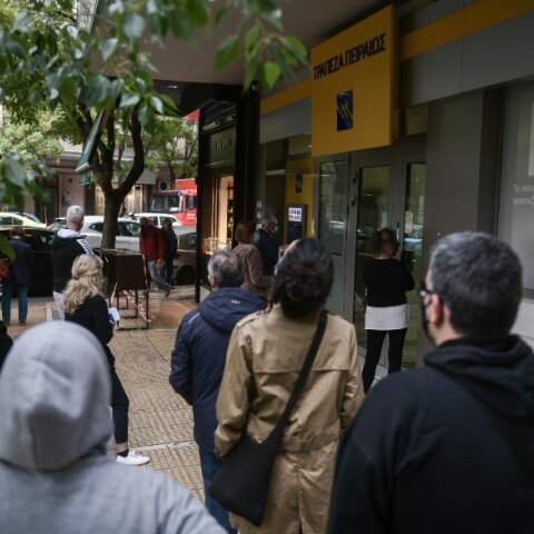 Πολίτες περιμένουν στην ουρά για να μπουν στην τράπεζα