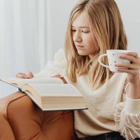 Νεαρή κοπέλα στον καναπέ, διαβάζει βιβλίο