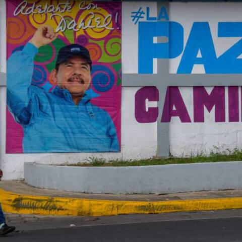 Μια γυναίκα περπατά μπροστά από διαφημιστική αφίσα με την εικόνα του Προέδρου της Νικαράγουας, Ντάνιελ Ορτέγκα