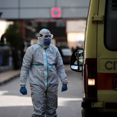 Τραυματιοφορέας με προστατευτική στολή για τον κορωνοϊό δίπλα σε ασθενοφόρο του ΕΚΑΒ 