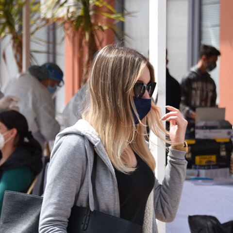 Κοπέλα με μάσκα περνά μπροστά από κινητό κλιμάκιο του ΕΟΔΥ που διενεργεί δωρεάν rapid test για κορωνοϊό