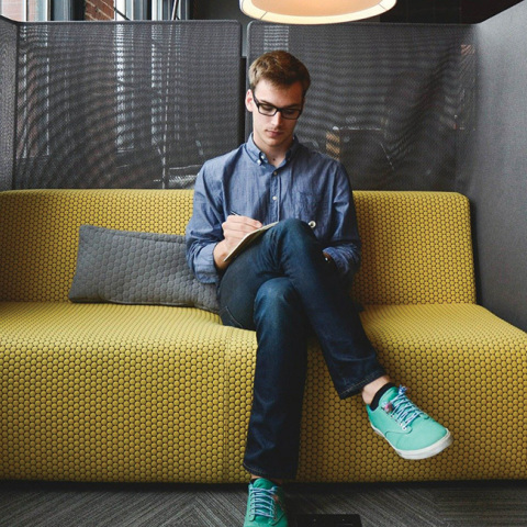 Νεαρός άντρας στον καναπέ εταιρείας, κρατάει σημειώσεις