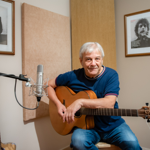 Ο Γιώργος Δημητριάδης κρατά ακουστική κιθάρα στο στούντιο