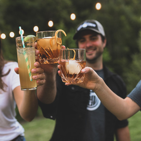 3 νεαροί φίλοι τσουκγρίζουν τα ποτήρια με το ποτό τους