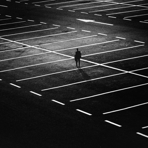 Ένας άντρας στέκεται στη μέση ενός άδειου πάρκινγκ τη νύχτα