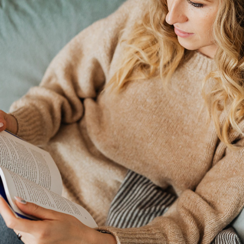 Μια γυναίκα κάθεται στον καναπέ και διαβάζει βιβλίο