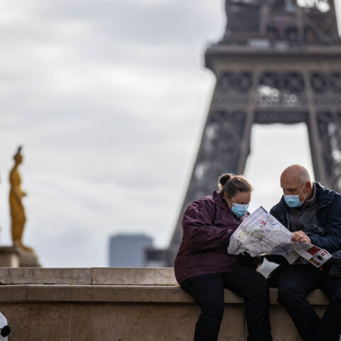Πολίτες στη Γαλλία με μάσκα για τον κορωνοϊό με φόντο τον Πύργο του Άιφελ