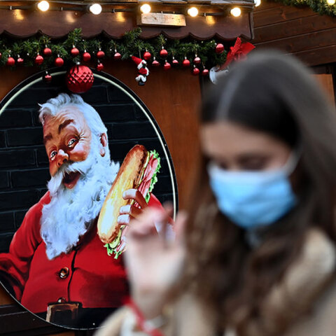 Κοπέλα με μάσκα για κορωνοϊό σε χριστουγεννιάτικη αγορά στο Λονδίνο
