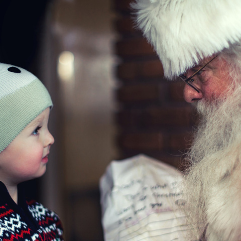 Ένα μικρό παιδάκι στέκεται μπροστά από τον Άγιο Βασίλη