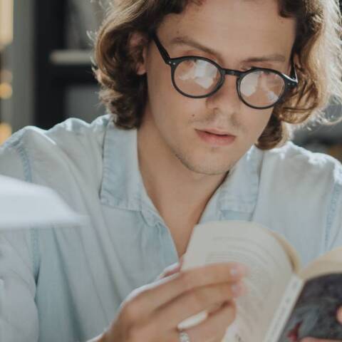 Νεαρός άντρας με γυαλιά, που διαβάζει βιβλίο
