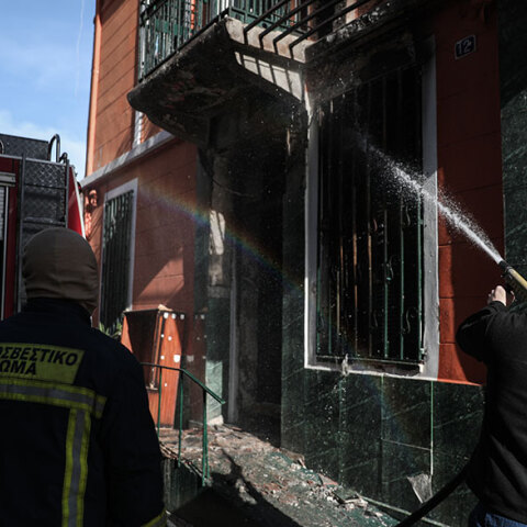 Πυροσβέστης ρίχνει νερό στο σπίτι που πήρε φωτιά στο Μεταξουργείο