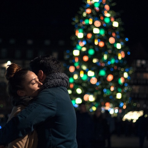 Ζευγάρι που αγκαλιάζεται με φόντο Χριστουγεννιάτικο δέντρο