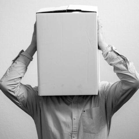 Ασπρόμαυρη φωτογραφία με έναν άντρα που έχει βάλει ένα κουτί στο κεφάλι του