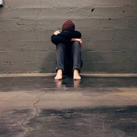 Ένα αγόρι κάθεται μόνο του κρύβοντας το πρόσωπό του